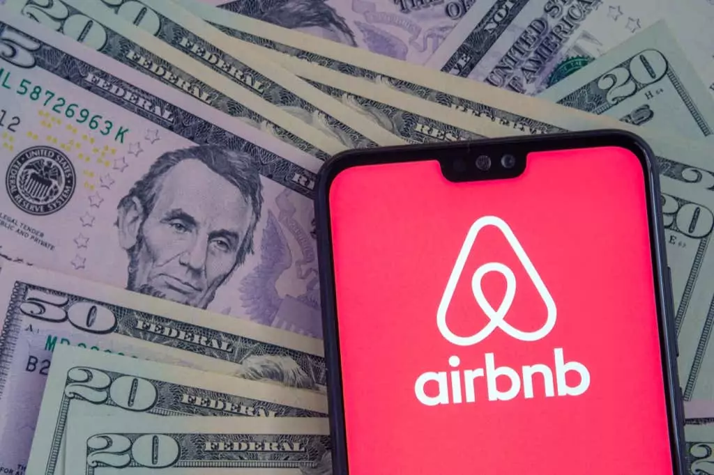 Stafford / Vương quốc Anh - Ngày 15 tháng 11 năm 2020: Logo ứng dụng Airbnb nhìn thấy trên màn hình điện thoại thông minh, đặt trên tờ đô la. - Mẹo công nghệ trực tuyến Cách tìm chỗ ở giá rẻ trên Airbnb