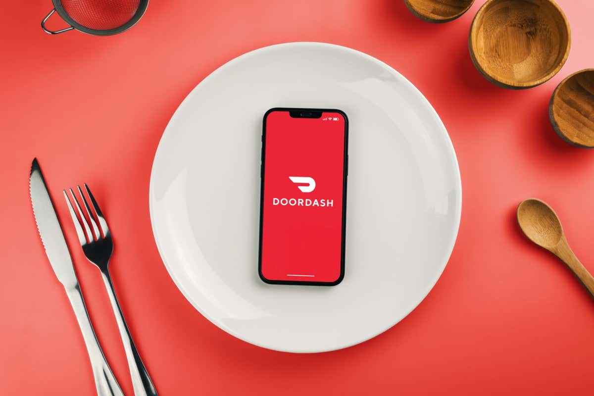 Ứng dụng giao hàng Doordash trên màn hình điện thoại thông minh trên tấm trắng. Bên cạnh dao kéo và đồ dùng. Đang chờ giao hàng để ăn đồ ăn. Rio de Janeiro, RJ, Brazil. Tháng 4 năm 2022 - Mẹo công nghệ trực tuyến Cách xóa thẻ thanh toán khỏi hình ảnh DoorDash