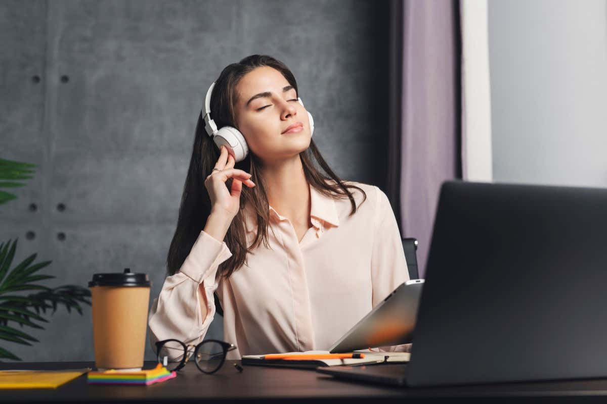 Cô gái đeo tai nghe thưởng thức âm nhạc trước máy tính xách tay. Chất lượng âm thanh tuyệt vời và thiết kế của tai nghe không dây. Nữ phát trực tuyến nội dung âm nhạc và giải trí thư giãn từ internet. - Mẹo công nghệ trực tuyến Đường cong Harman là gì (và nó cải thiện chất lượng âm thanh tai nghe như thế nào)? hình ảnh